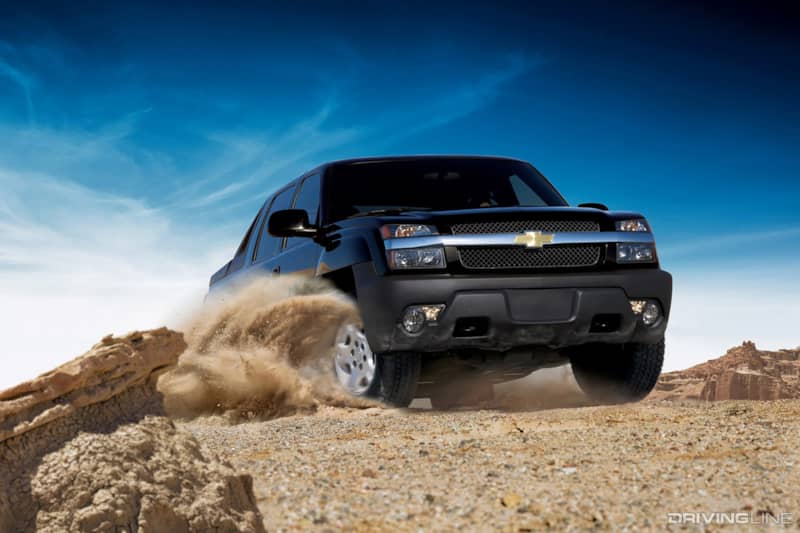 Chevy Avalanche pickup truck parked on a paved surface, angled slightly toward the viewer; tree-lined background under a clear blue sky; no visible text; conveys a rugged, utilitarian and versatile tone